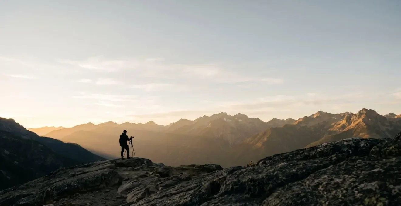 Photographe solitaire face à un panorama de montagne spectaculaire à l'aube dans une atmosphère paisible