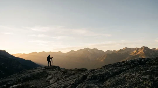 Photographe solitaire face à un panorama de montagne spectaculaire à l'aube dans une atmosphère paisible