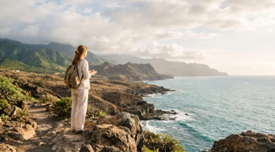 Voyageur contemplant un paysage volcanique et côtier ensoleillé depuis un point de vue des Canaries, symbolisant le choix d'une île pour l'hivernage