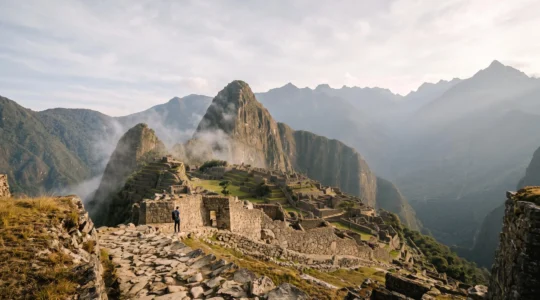 Vue panoramique de la cite inca du Machu Picchu enveloppee de brume au lever du jour, illustrant les vestiges archeologiques de la civilisation inca
