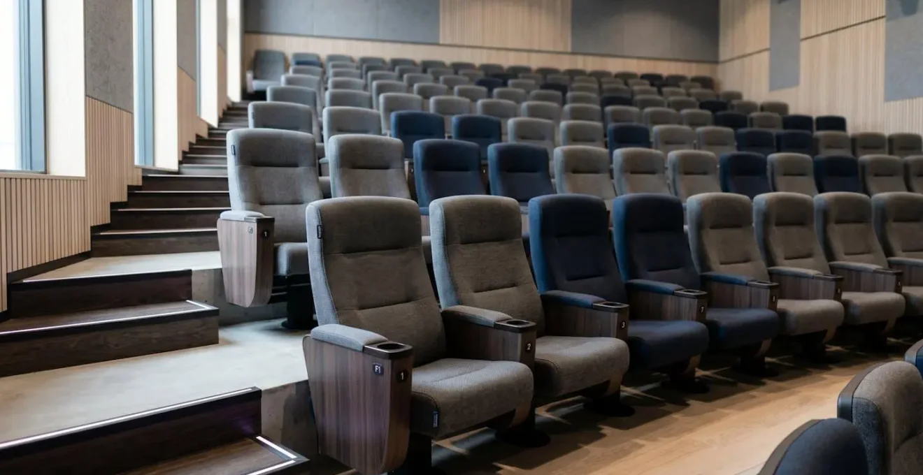 Rangée de fauteuils confortables en gradins dans auditorium, montrant ergonomie et disposition étagée garantissant visibilité parfaite.